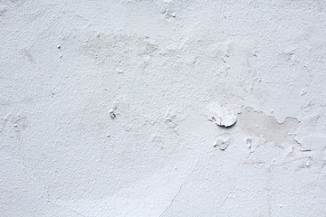 An old white wall with peeling paint. Urban texture. Old white plaster. Stucco wall, grungy background.