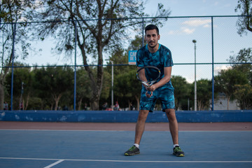 Obraz premium Hombre adulto latino con barba de camiseta azul en pantaloneta jugando tenis con amigo en cancha profesional hispano