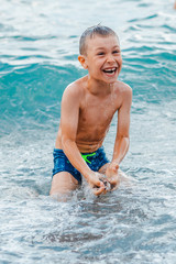 little girl in a swimsuit splashing her legs in the sea