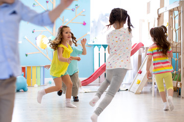 Children games in playroom. Kids play and run after each other. Group of kids in day care.