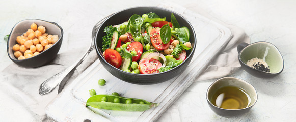 Vegan salad with cucumber, tomato, spinach, lettuce, onion, green pea and chickpea