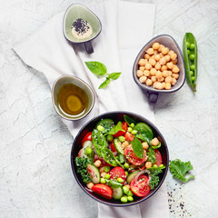 Vegan salad with cucumber, tomato, spinach, lettuce, onion, green pea and chickpea