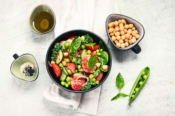 Vegan salad with cucumber, tomato, spinach, lettuce, onion, green pea and chickpea