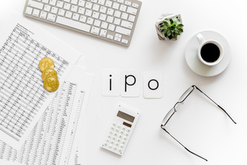IPO with coins, calculation table, keyboard, coffee on office desk white background top view
