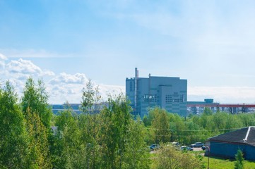 Obraz premium Summer industrial landscape - the roofs of industrial buildings against the blue sky with white clouds