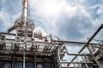 Fototapeta premium Oil and gas industrial refinery zone,Detail of equipment oil pipeline steel with valve from large oil storage tank at cloudy sky. -image