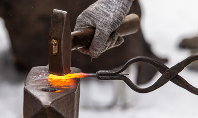 A blacksmith bends metal with a hammer