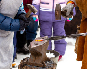 A blacksmith bends metal with a hammer