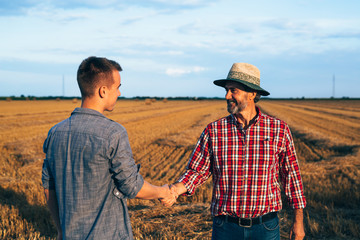 partnership handshake. two ranchers handshake on field