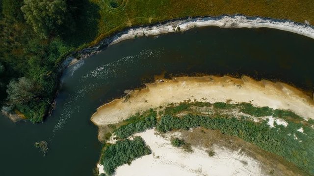 Aerial view of a man in a protective suit and a respirator who collects plastic trash on the banks of a dry and polluted river. Ecological catastrophy. Anthropogenic influence. 4K drone footage.