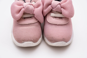 On a white background pink baby female sneakers, copy space