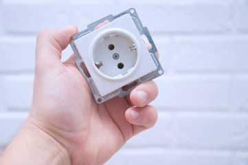 The guy holds a socket in his hand against a white loft.