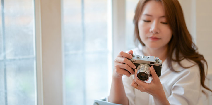 Beautiful young photographer checking her camera while working on her project