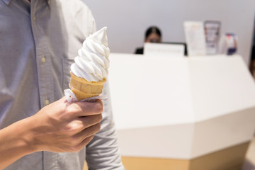 Young men holding vanilla ice cream cone in shopping mall , Bangkok , Thailand..