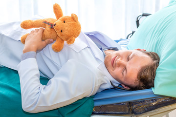 Obraz premium Pediatrician (doctor) sleeping and hug teddy beer on bedroom hospital. Good dream and relax.