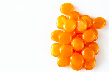 Closeup of hard sucking fruit candies on a white background. A bunch of orange candies. Copy space. Top view