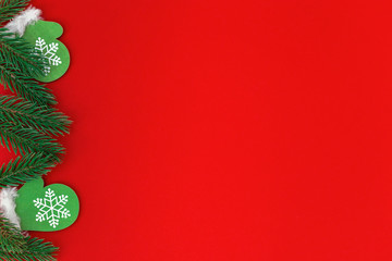 Small wooden christmas toy Green mittens with pine branches on red paper background with copy space. Christmas greeting card.