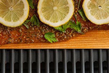 A piece of fish steak with lemons lies on a wooden board, baked, closeup