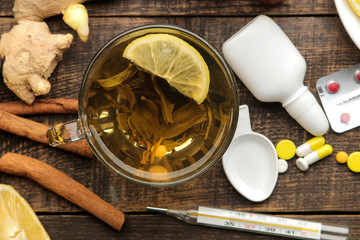 Medicines, pills, cough syrup, thermometer and folk remedies for the treatment of influenza and the common cold on a brown wooden table. top view