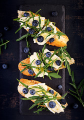 Bruschetta. Toast crostini with fresh berries blueberry and honey, brie cheese, arugula. Top view, copy space.