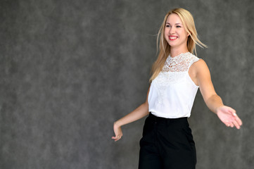 Portrait of a pretty blonde girl in a white blouse on a gray background. Beauty, brightness, happiness. Shows different emotions in different poses.