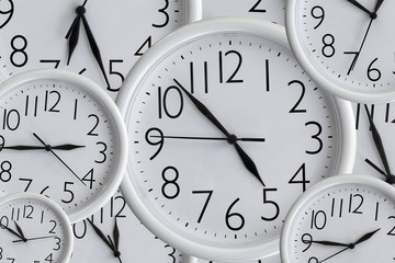Background from set of white analog round office clocks of different sizes showing various time