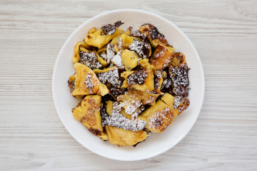 Homemade german Kaiserschmarrn pancake on a white plate over white wooden background, top view. Flat lay, overhead, from above.