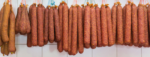 Many dried sausages on the hook in the butcher shop, banner