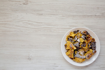 Homemade german Kaiserschmarrn pancake on a white plate on a white wooden background, overhead view. Flat lay, top view, from above. Copy space