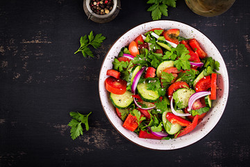 Tomato and cucumber salad with red onion, paprika, black pepper and parsley. Vegan food. Diet menu. Top view. Flat lay