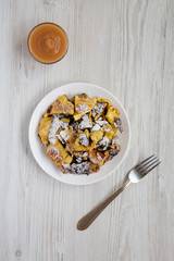 Homemade german Kaiserschmarrn pancake with apple sauce on a white wooden surface, top view. Flat lay, overhead, from above.