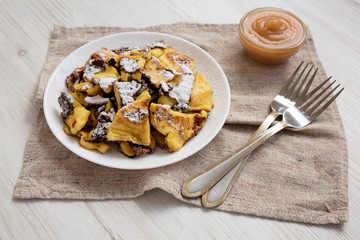 Homemade german Kaiserschmarrn pancake with apple sauce on a white wooden background, side view. Close-up.