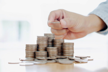 Hand giving coins into stack, business and finance concept