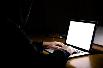 Photo of young concentrated man using laptop computer at home indoors at night. Looking at laptop display.