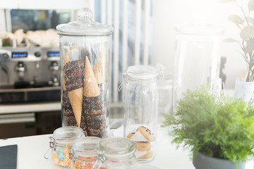 Cone and topping in the glass bottles in the white cafe.