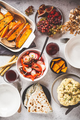 Flat lay of vegan food: baked sweet potato, cauliflower, fruits, vegetable salad and tortilla with greens on white background.