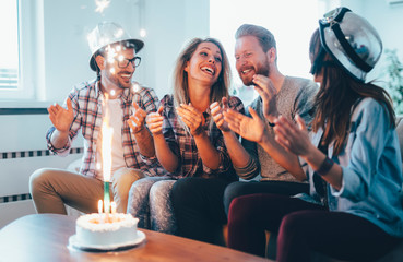 Group of happy friends celebrating birthday at home together