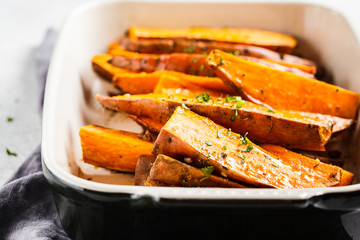 Baked sweet potato slices with spices in oven dish. Healthy vegan food concept.