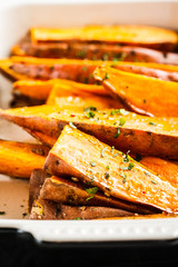 Baked sweet potato slices with spices in oven dish. Healthy vegan food concept.