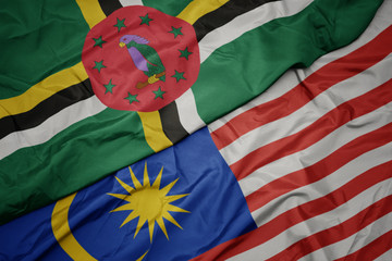 waving colorful flag of malaysia and national flag of dominica.