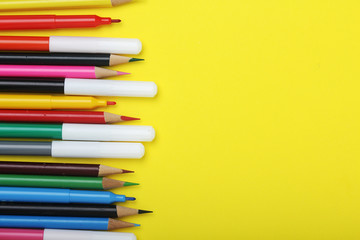 Multicolored markers and pencils at bright background