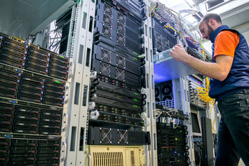 Technician repairs the central router. Man works in a server room. System administrator installs a...