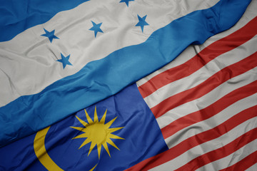 waving colorful flag of malaysia and national flag of honduras.