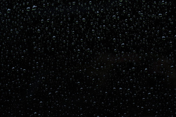 Water raindrops on a shiny dark black surface