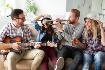 Group of young friends having fun together and playing in music band