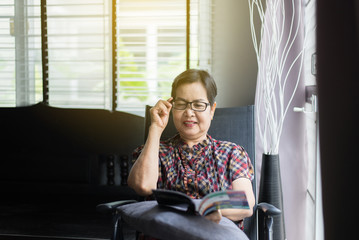 Mature asian woman wearing glasses and reading a book at home,Relax time,Senior lifestyle concept