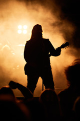 A heavy metal star playing guitar. Hard rock guitarist in concert.