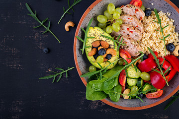 Fototapeta na wymiar Buddha bowl dish with meatloaf, bulgur, avocado, sweet pepper, tomato, cucumber, berries and nuts. Detox and healthy superfoods bowl concept. Overhead, top view, flat lay