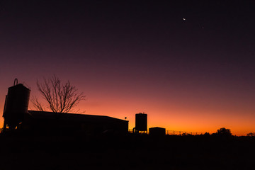 Obraz premium silhouette of a dairy farm building at sunset on a dairy farm, victoria, australia