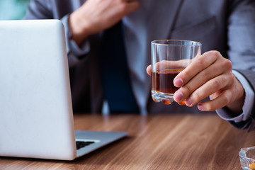 Male employee drinking alcohol and smoking cigarettes at workpla